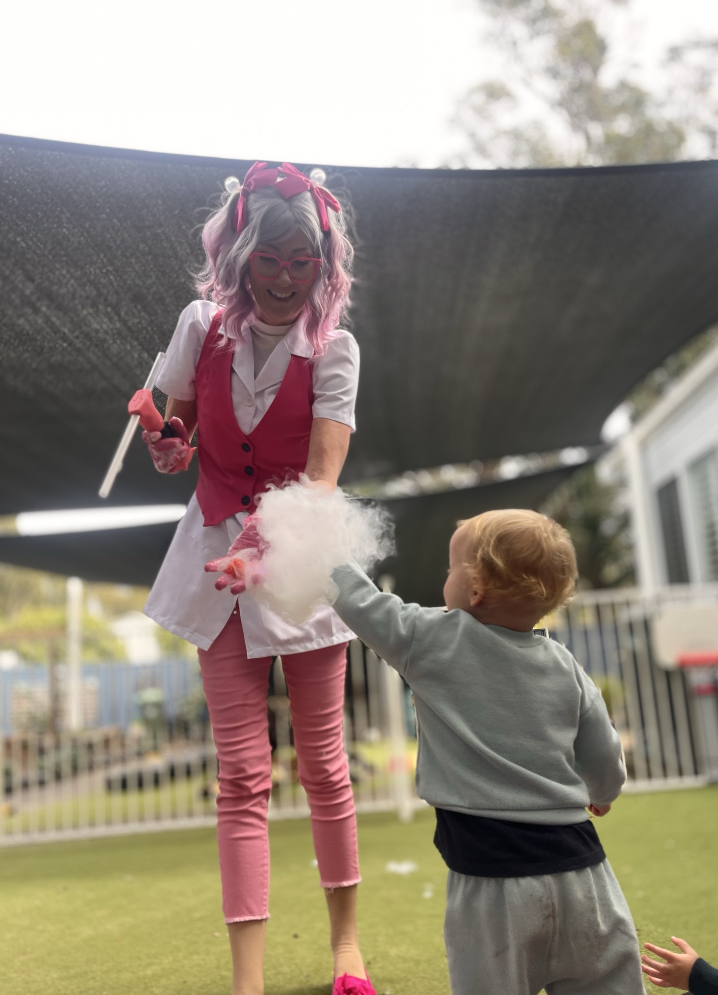 A young Lakeview child reaching towards a sensory bubble experiment with Professor Pop